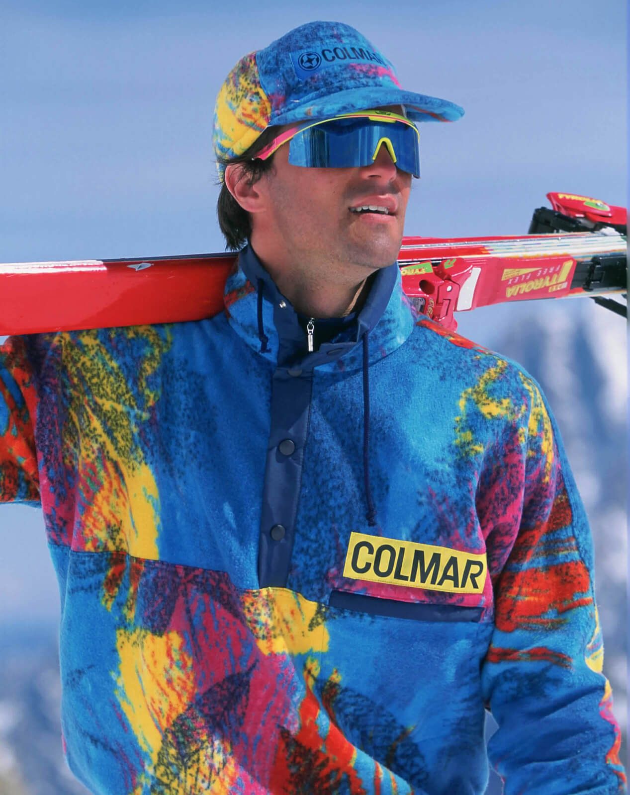man with sunglasses and skis on his shoulder