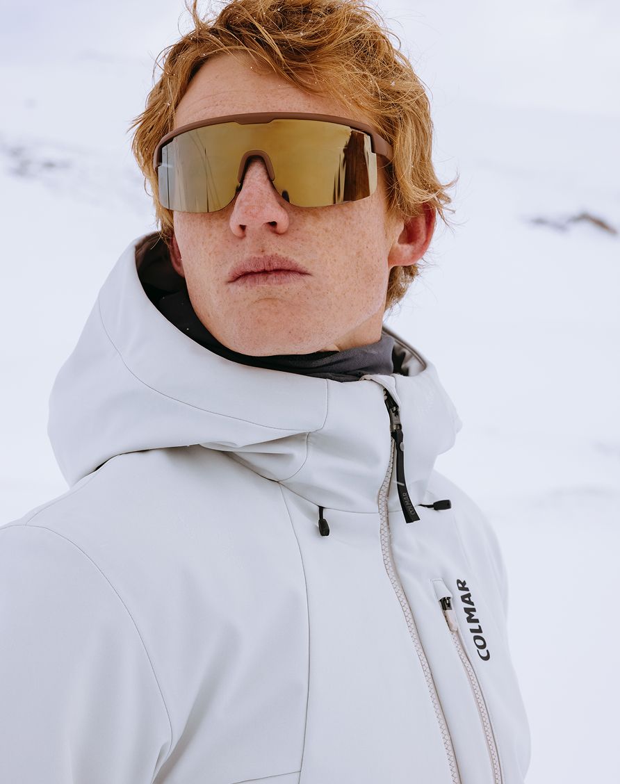 Uomo sulla neve con giacca bianca