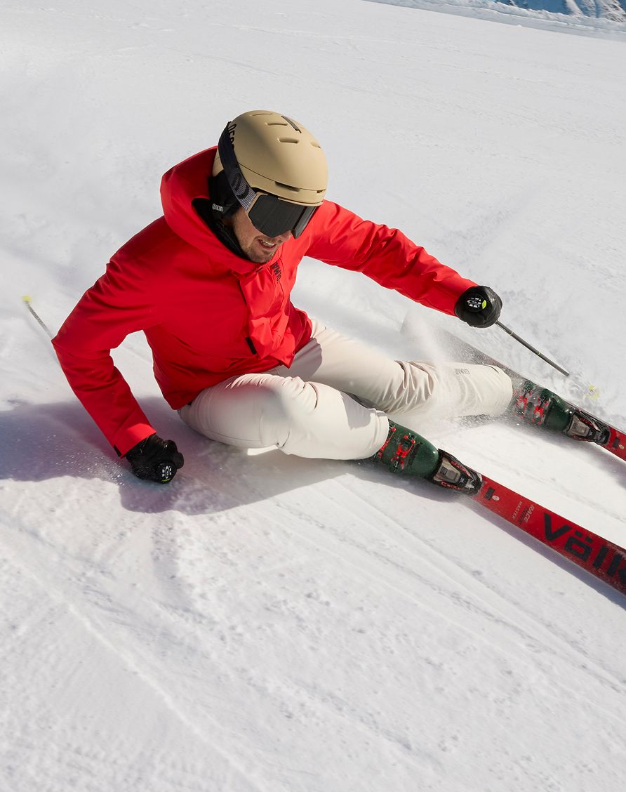 Uomo sulla neve con giacca rossa che scia