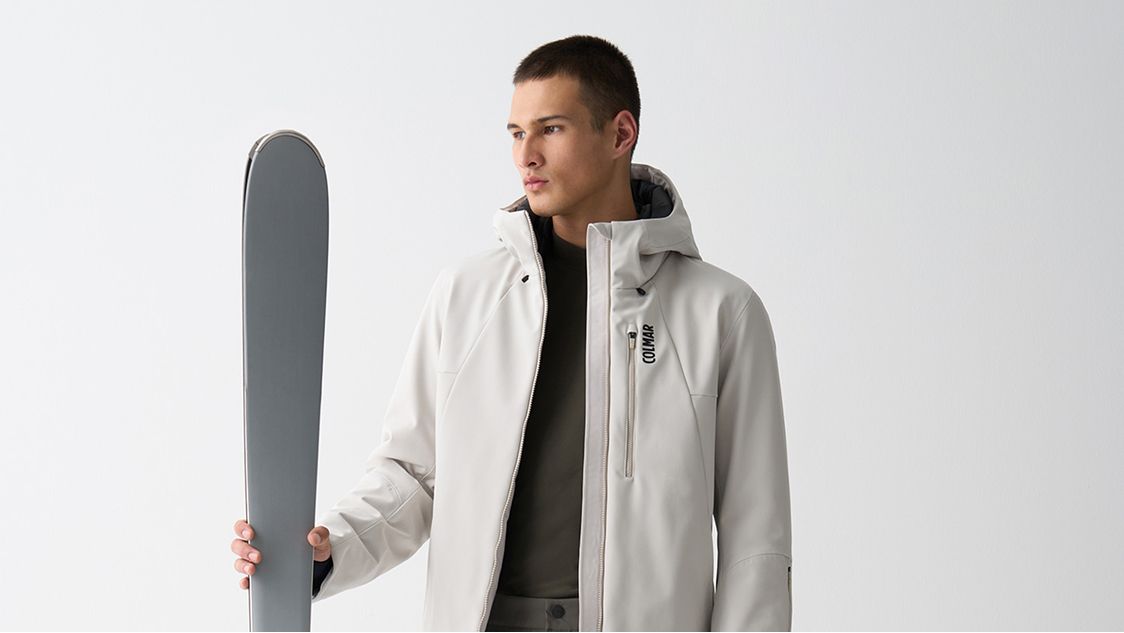 Uomo con giacca bianca e sci