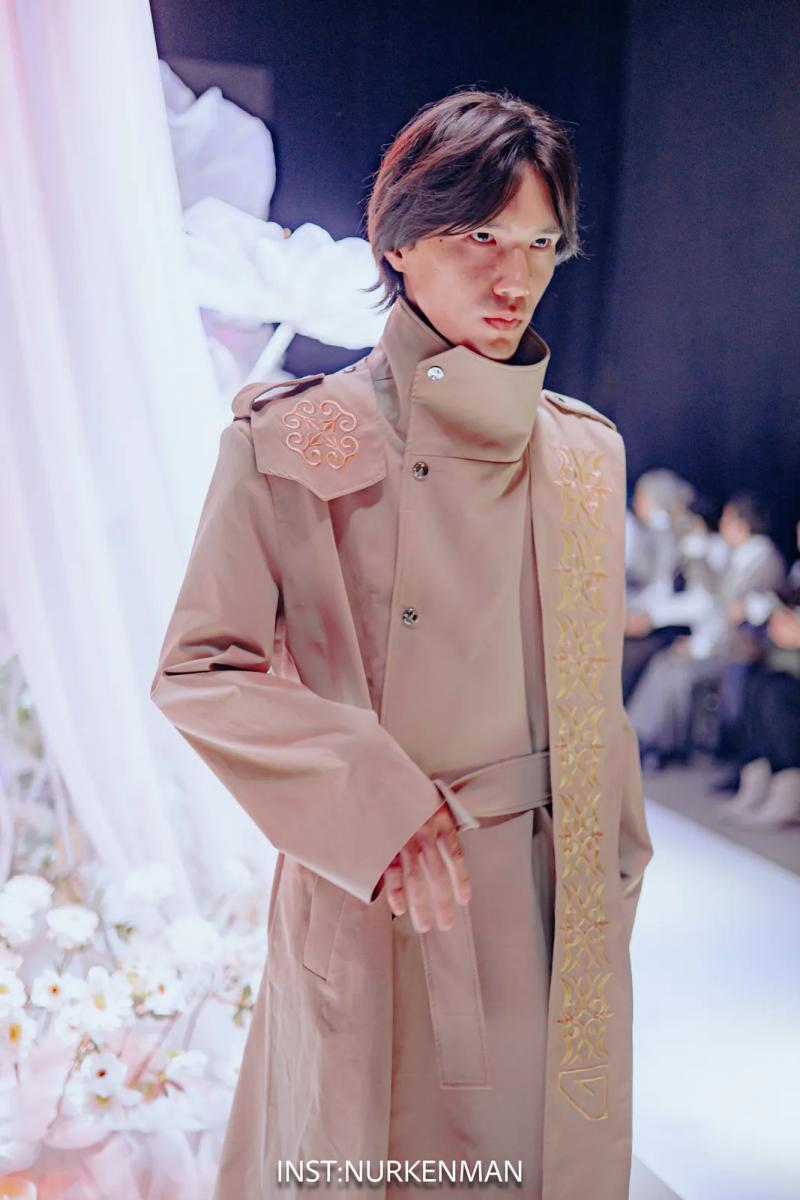 Model in a beige trench coat with embroidered ornament