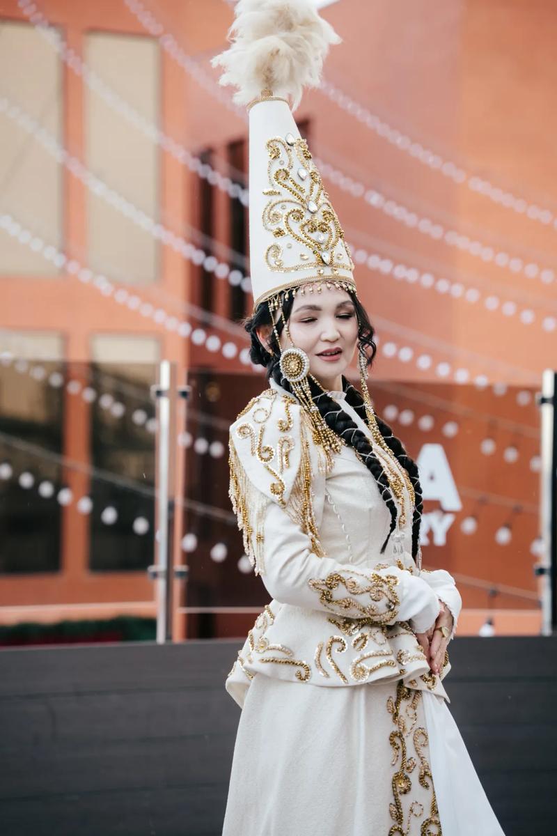 Model in a white national dress and a saukele headdress, outdoors