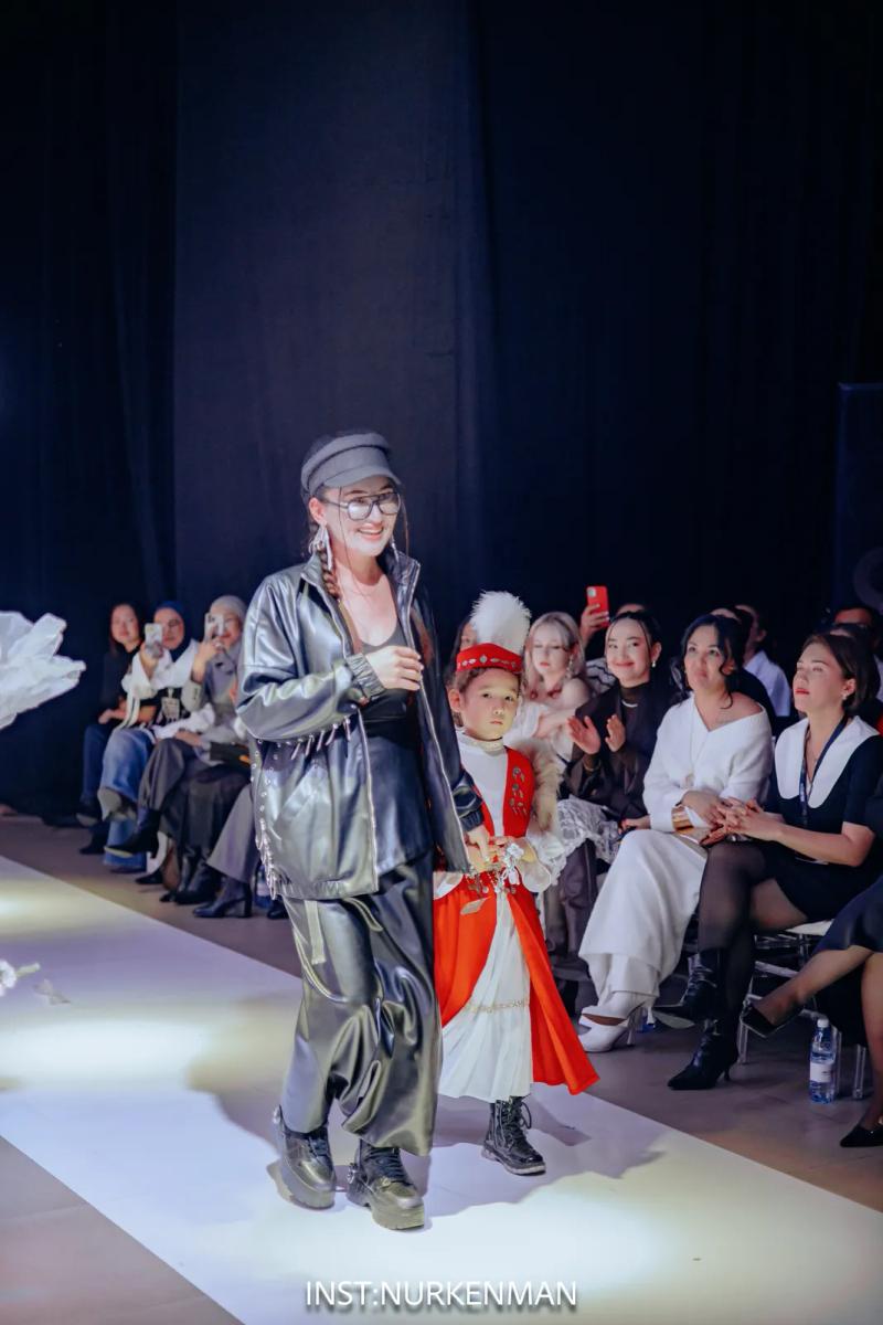 Banu Gaidar walks the runway at the end of the show with a child in national dress