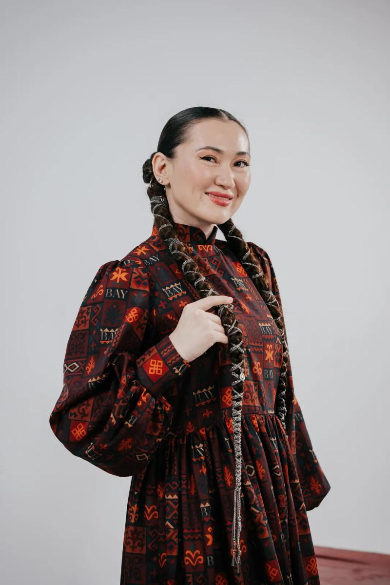 Banu Gaidar in a dark red dress with Kazakh ornament, studio portrait