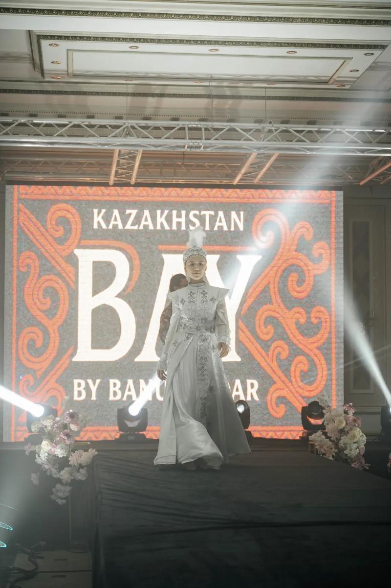 Model in a white national dress and headdress on the runway