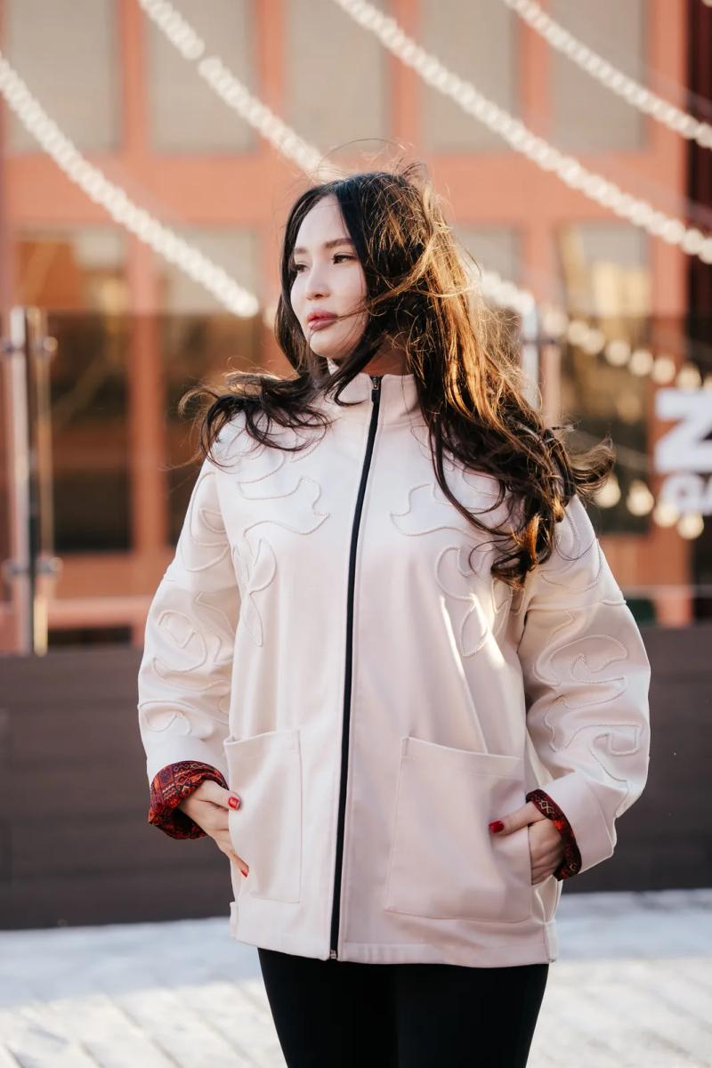 Model in a cream jacket with corded ornament, outdoors