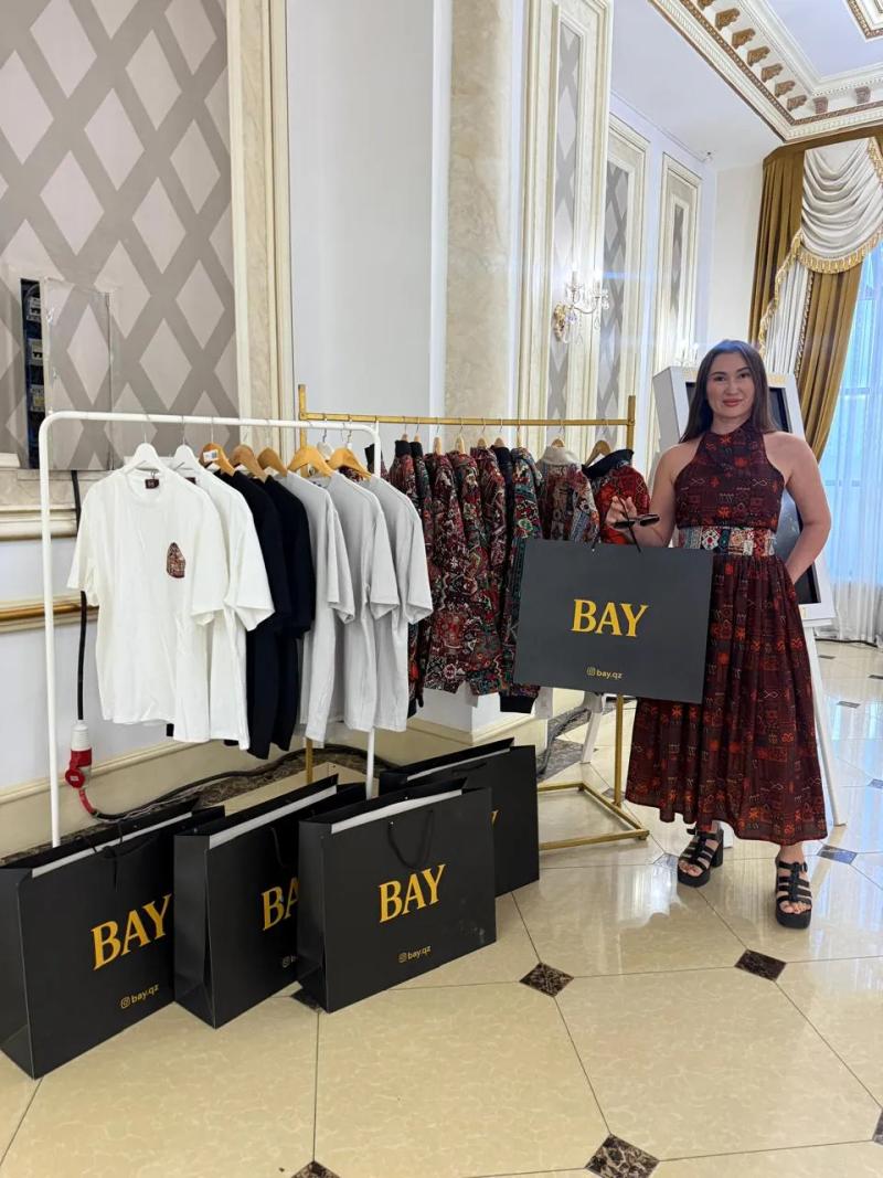 Banu Gaidar beside a rail of BAY clothes and BAY bags