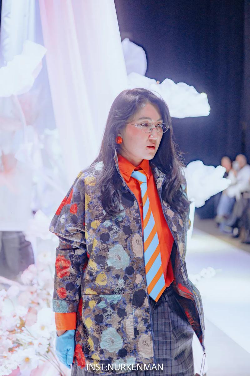 Model in a bomber with a floral pattern and a striped tie