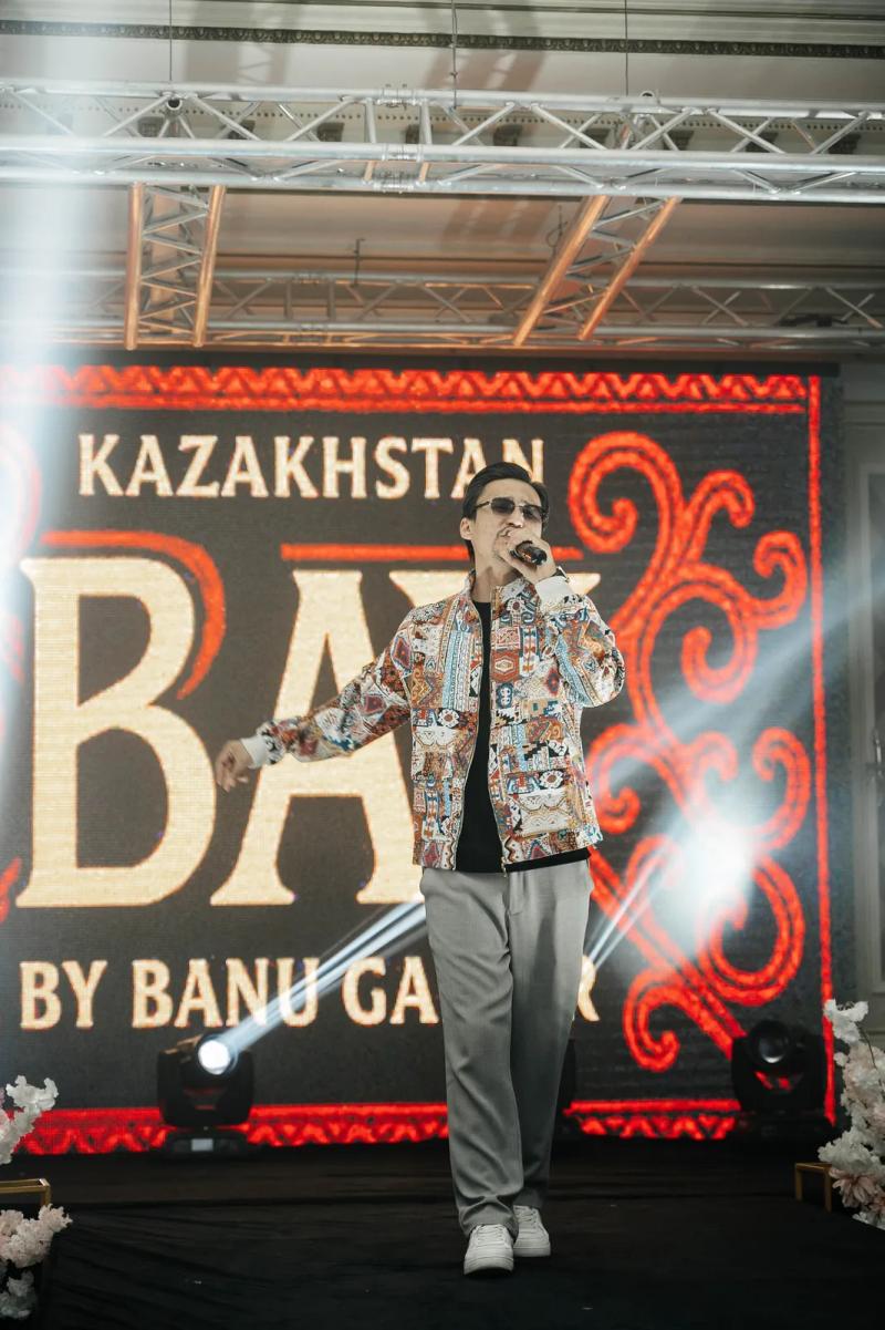 A man in a BAY bomber with a microphone on the runway