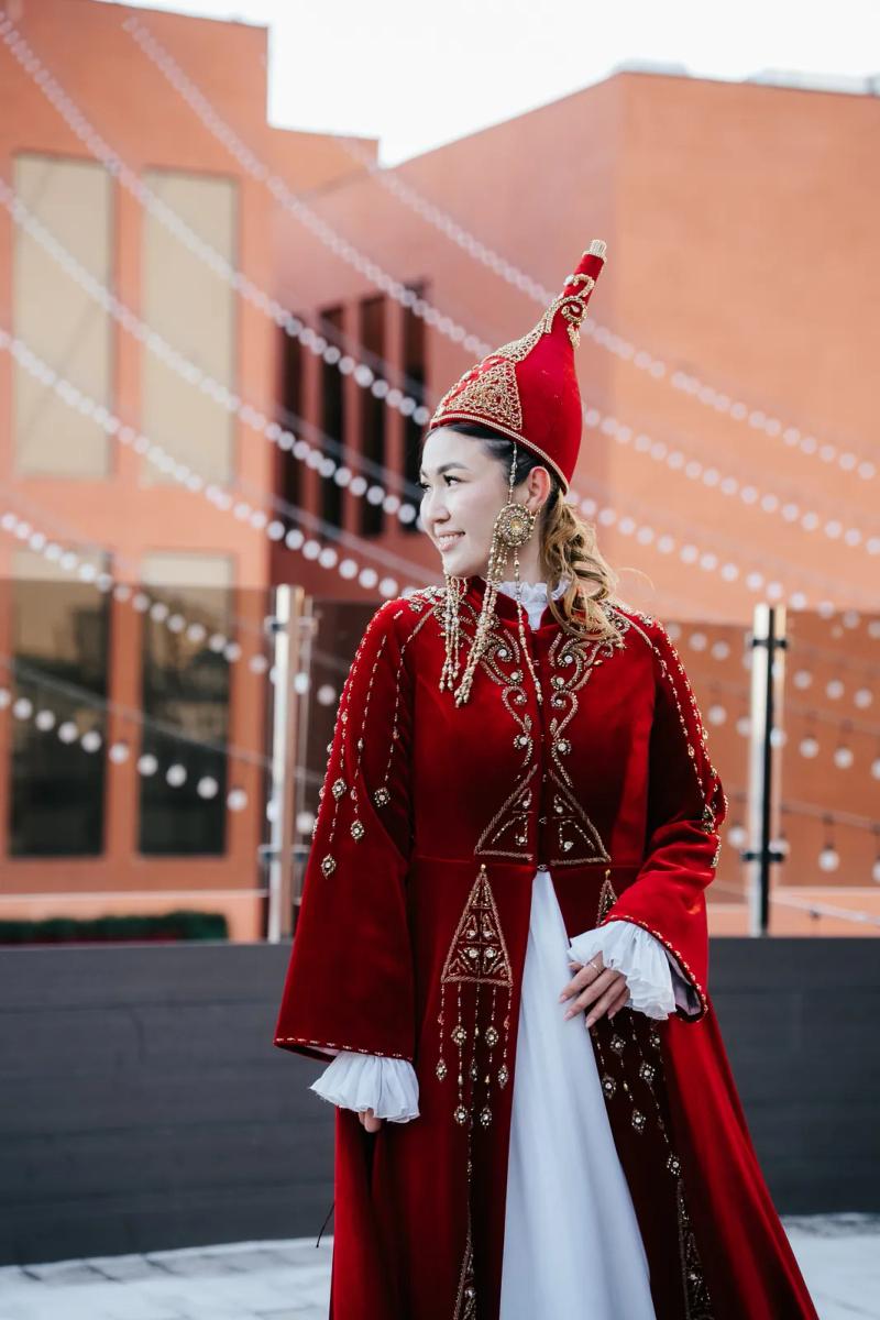 Model in a red national coat and headdress, outdoors