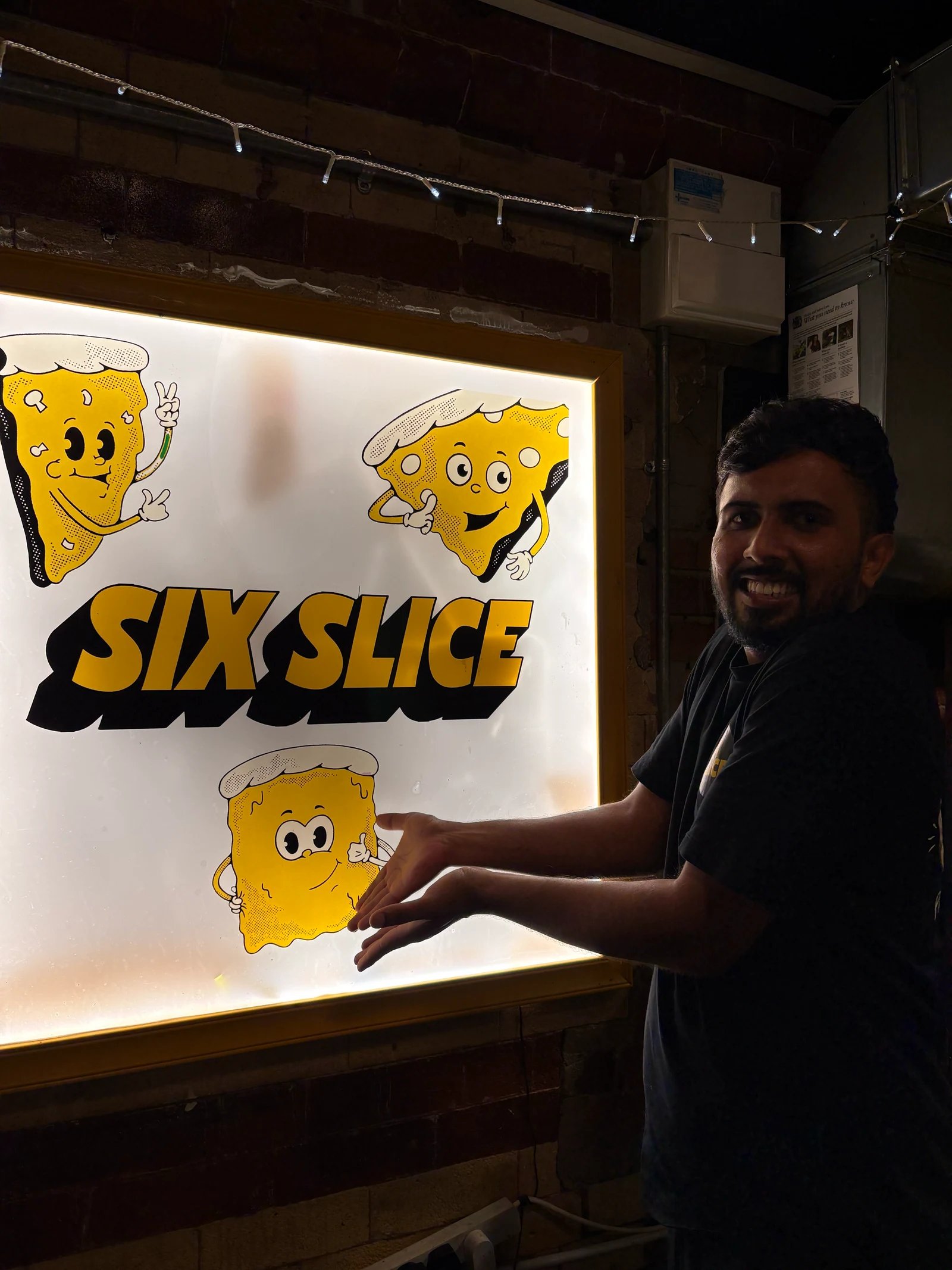 A person beside the illuminated Six Slice sign at Northern Market