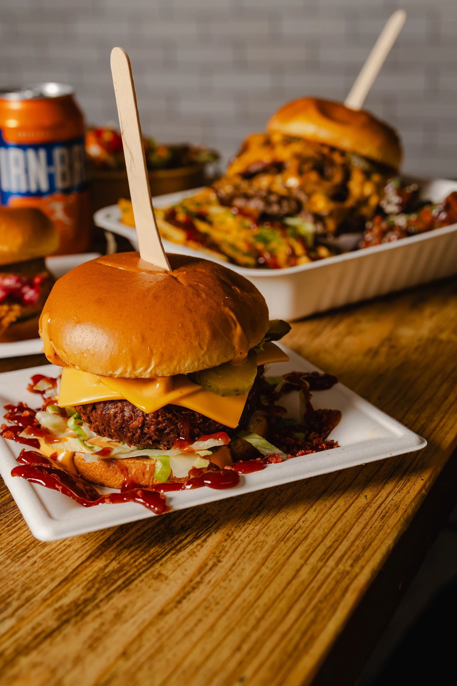 Two burgers and loaded fries photographed on a wooden Northern Market table