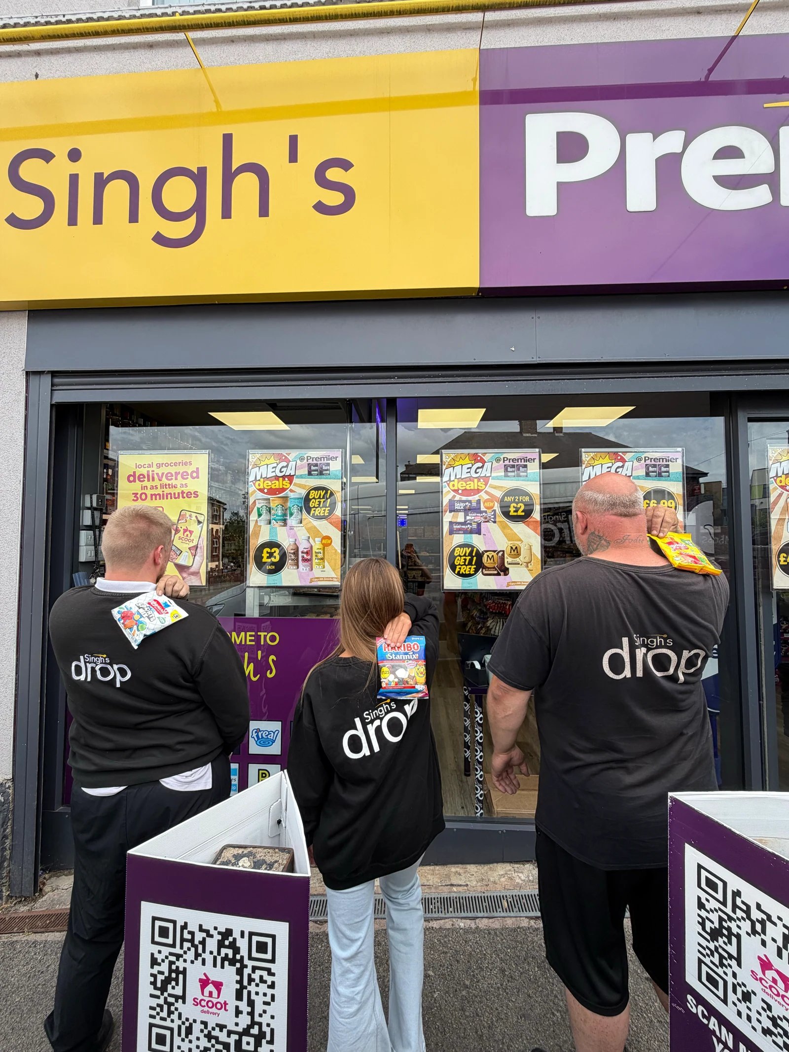 Three people wearing Singh's Drop branded tops outside a Singh's Premier shop
