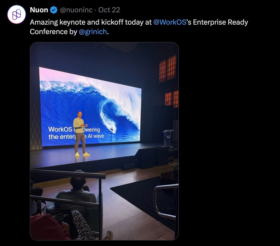 WorkOS's Keynote speaker giving the keynote with a screen showing a title page with a cool wave behind it