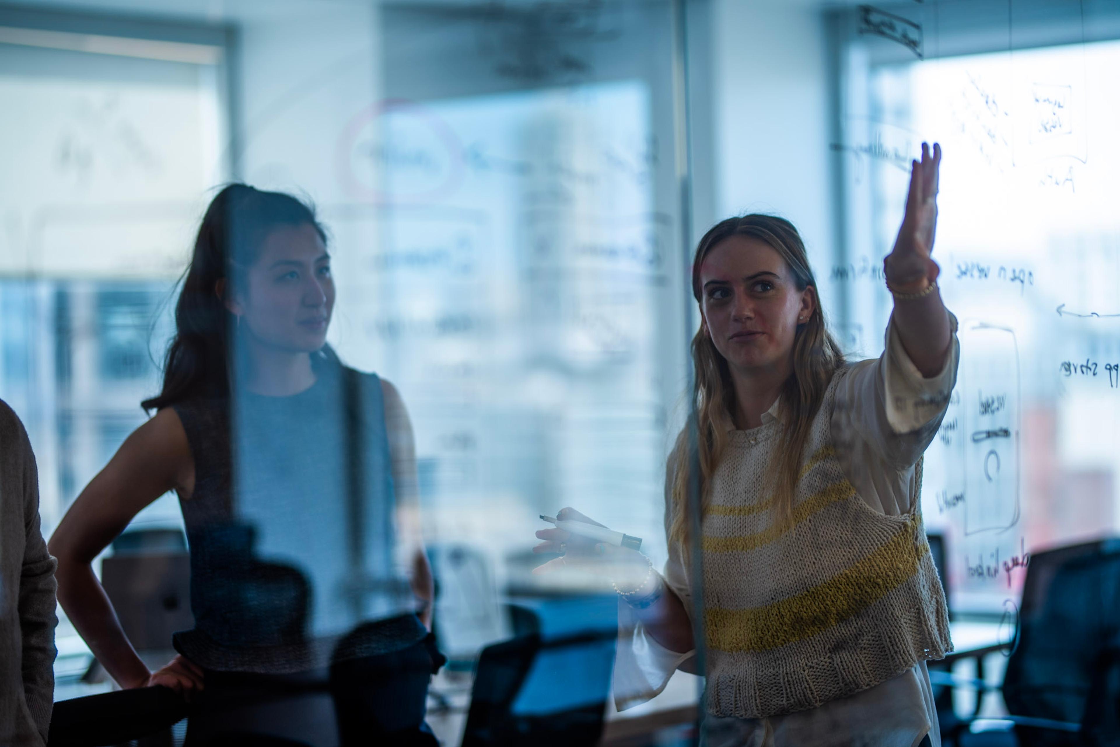 coworkers discussing an idea on a whiteboard