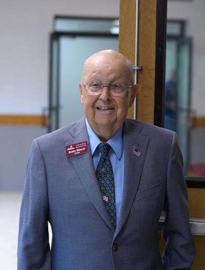 A smiling elderly man named Bobby Medlin, an usher for Calvary Road Baptist Church, wearing a suit and tie.