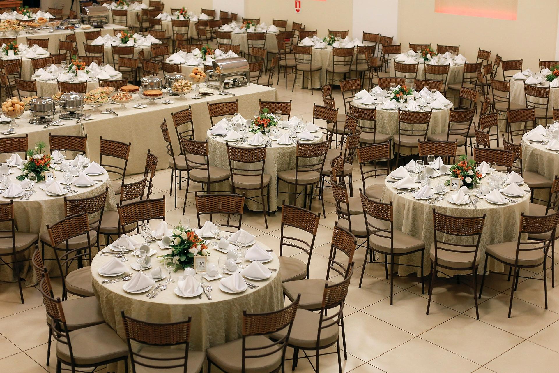 Spacious banquet hall setup with neatly arranged round tables and floral centerpieces, ready for a large event