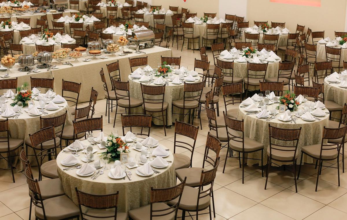 Spacious banquet hall setup with neatly arranged round tables and floral centerpieces, ready for a large event