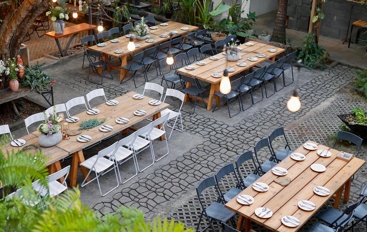 Scenic outdoor venue setup with rustic tables and floral decorations