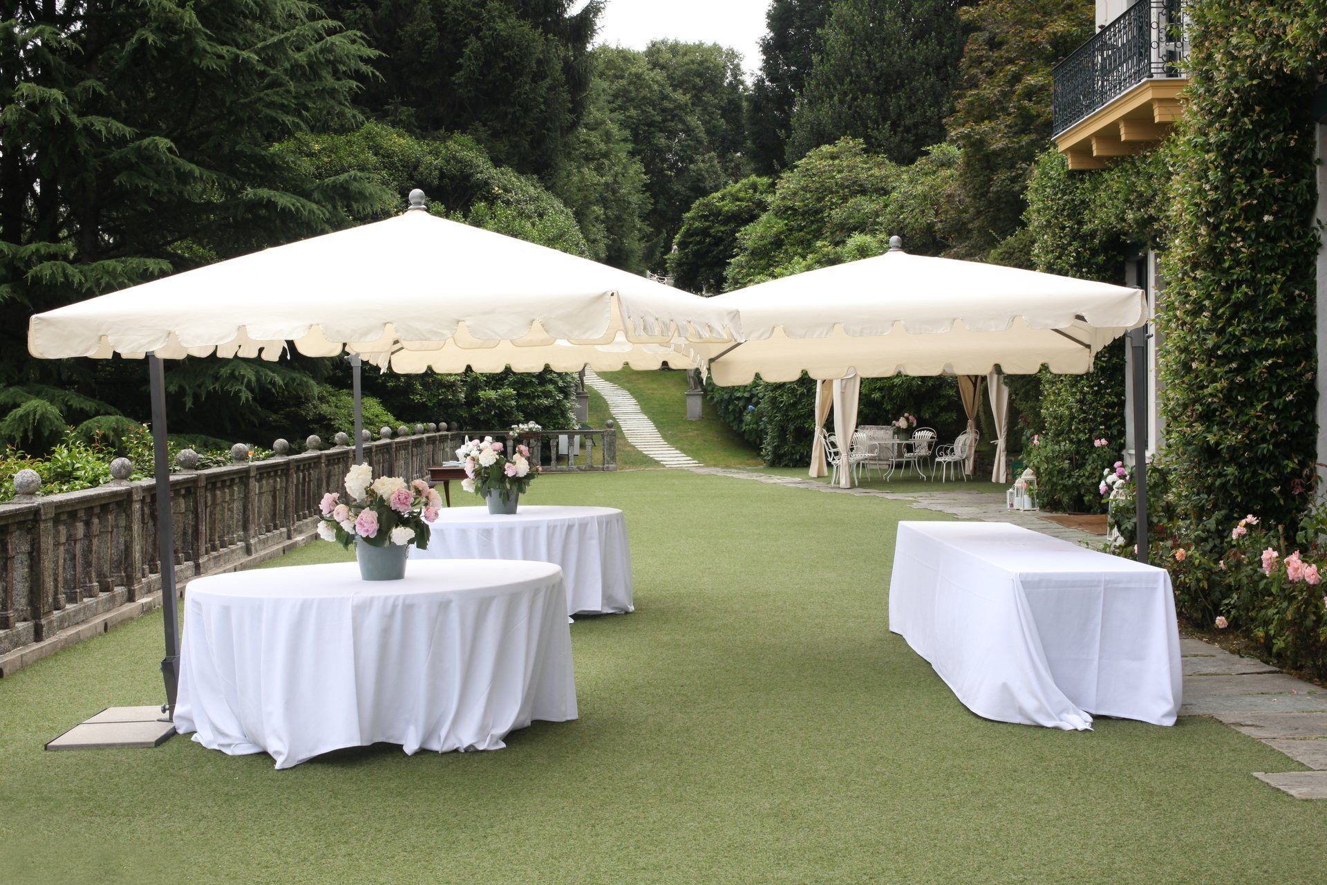 Cocktail-style outdoor setup with linen-draped standing tables under umbrellas