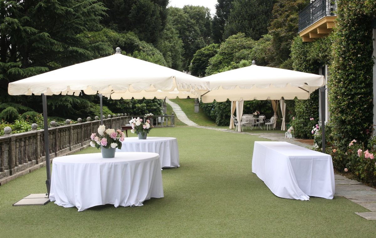 Cocktail-style outdoor setup with linen-draped standing tables under umbrellas