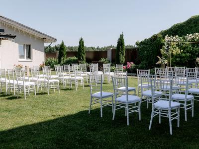 White chairs arranged in a garden setting for an outdoor wedding ceremony
