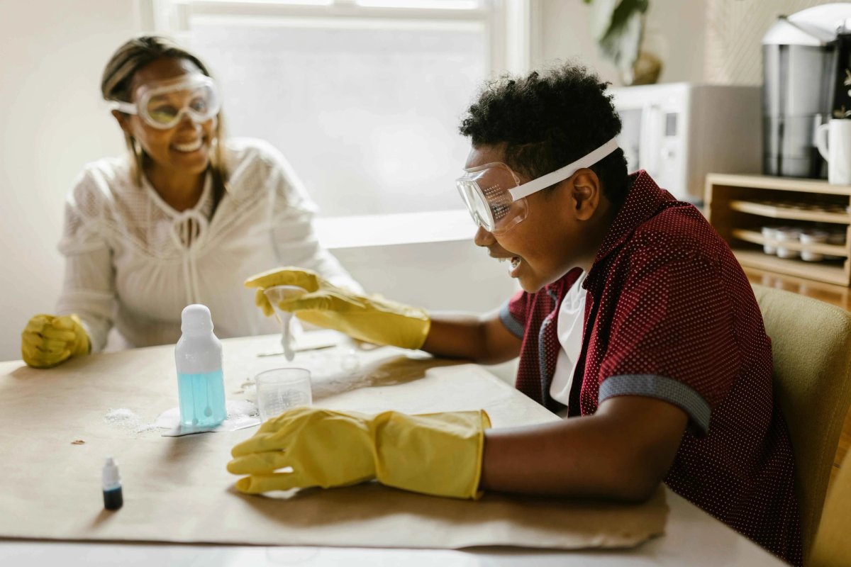 Enfant et adulte réalisant une expérience scientifique ensemble, symbolisant l'apprentissage et la découverte.