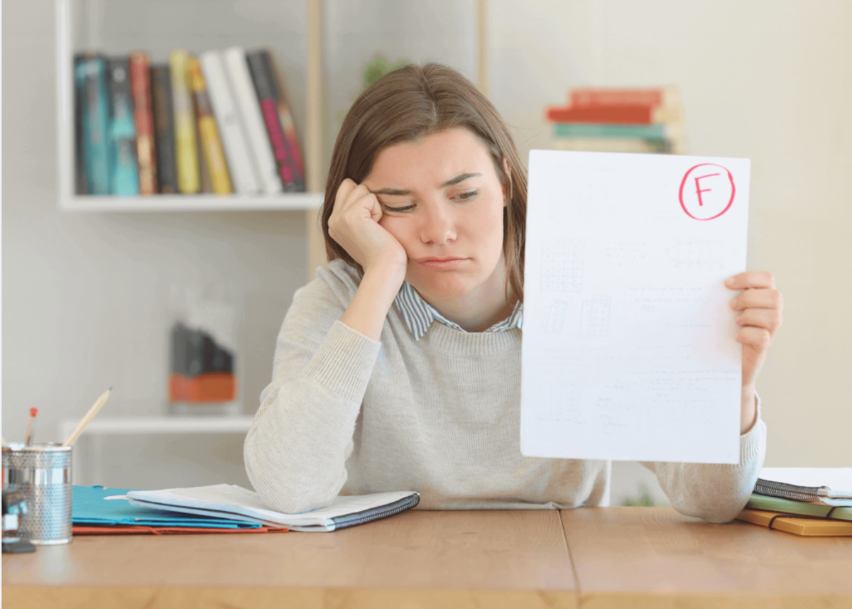 Adolescent appuyée sur le bureau montre son résultat d'examen (F) l'air decouragé. Elle a coulé son examen.