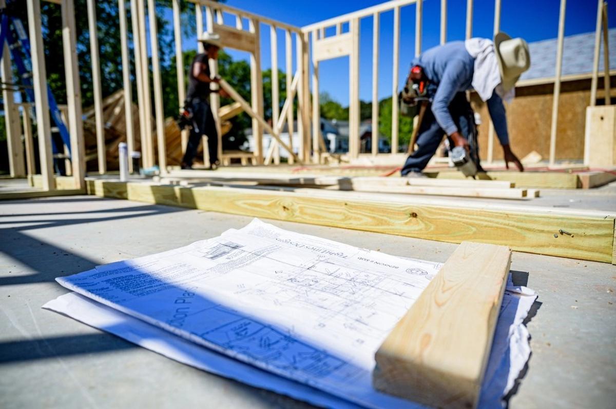 Obrero armando la estructura de una casa junto a los planos