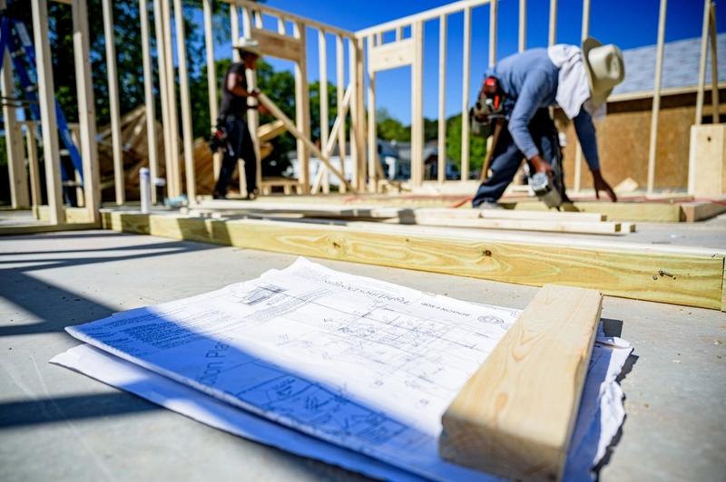 Obrero armando la estructura de una casa junto a los planos