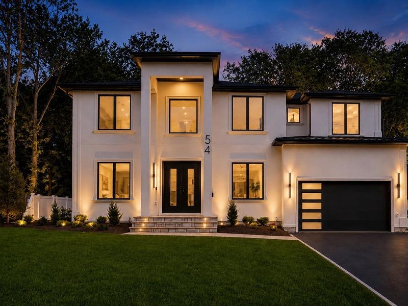 54 Martin Rd at dusk: white two-story house with lit windows and a two-car garage