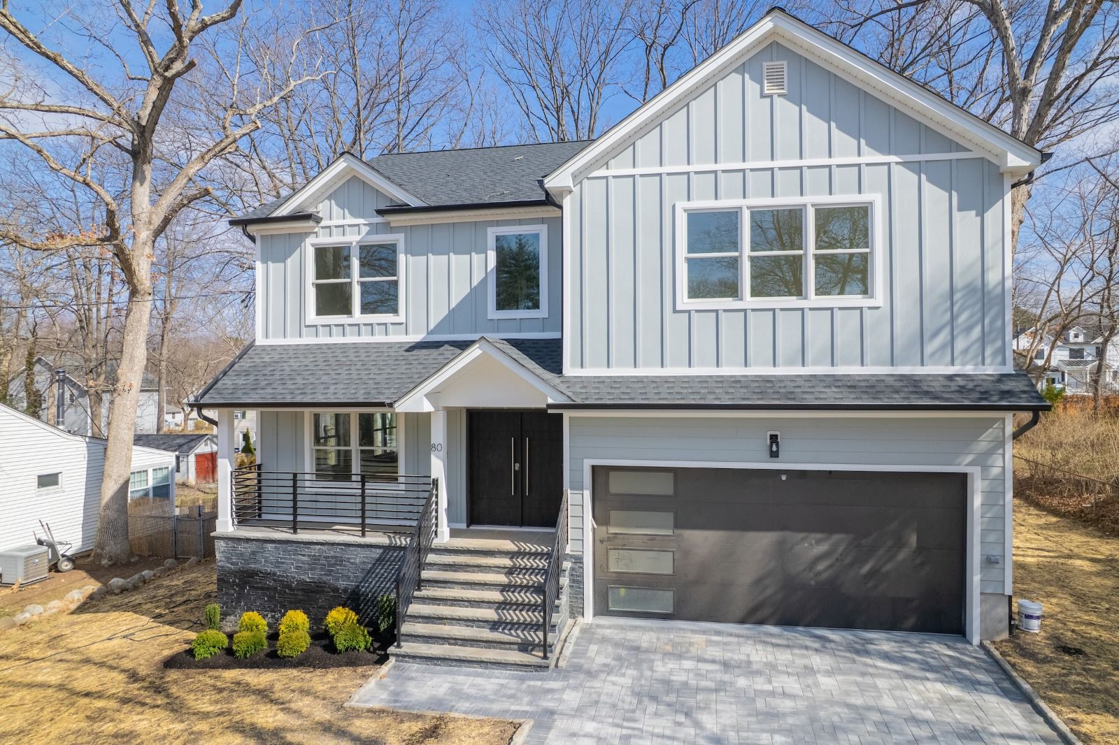 Front of 80 Irving Ave: two-story house with board-and-batten siding, front porch and two-car garage