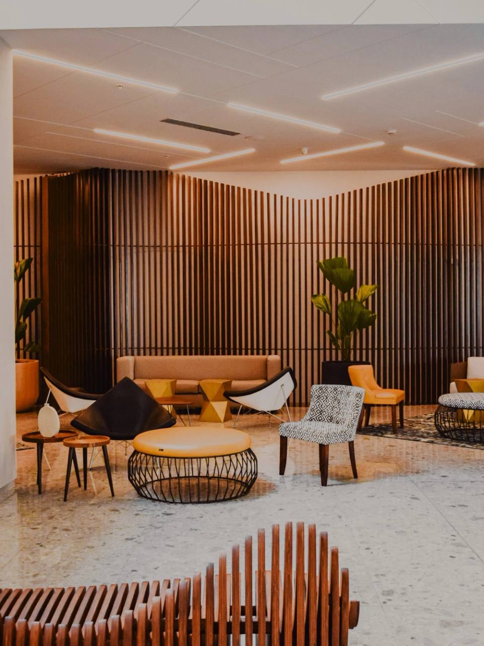Lobby z drewnianymi lamelami na ścianach i designerskimi fotelami