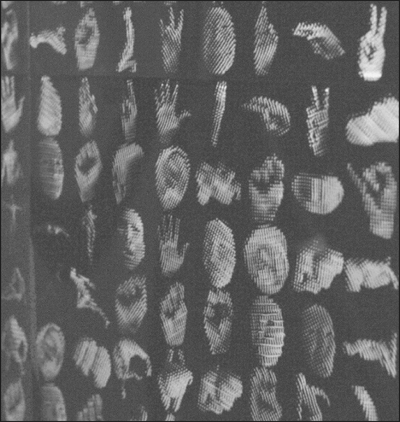 A blurred image of many faces and hands in black and white.