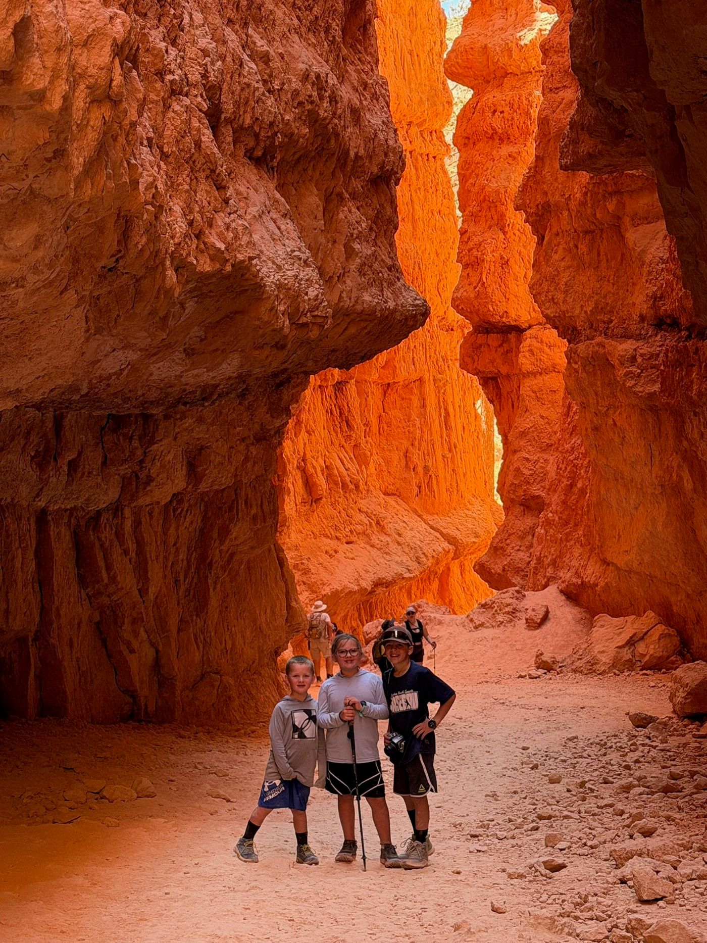 Three children on a trail between orange canyon walls.