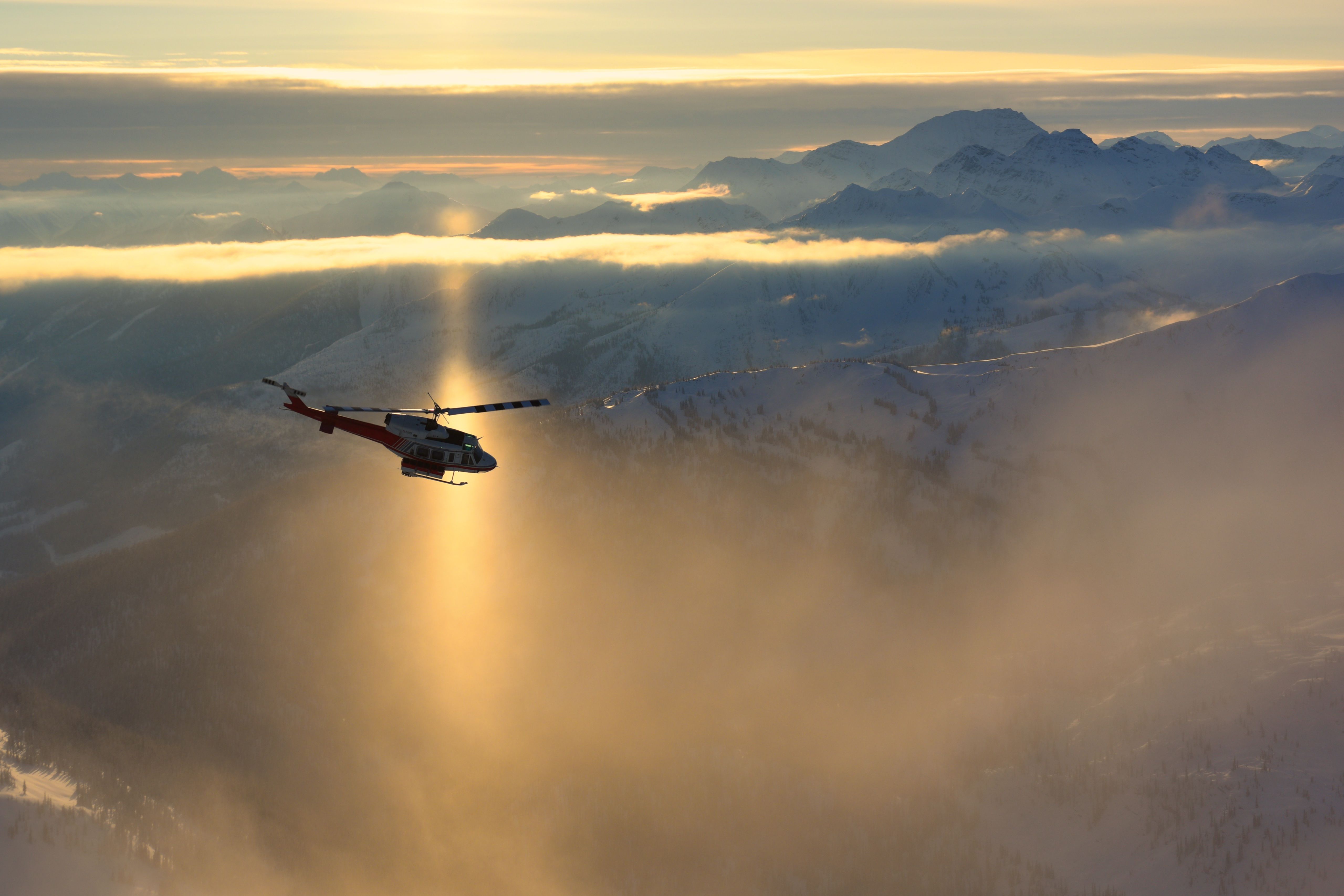 Helicopter flying over sunlit mountains