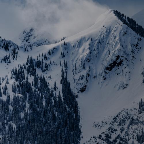 mountain range covered in snow and under a cloud