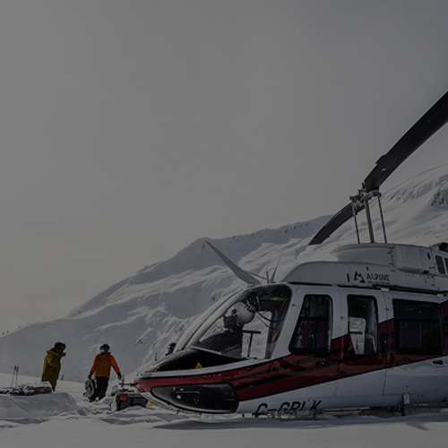 Helicopter parked on a snowy mountain plateau with several people in colourful winter gear standing nearby.