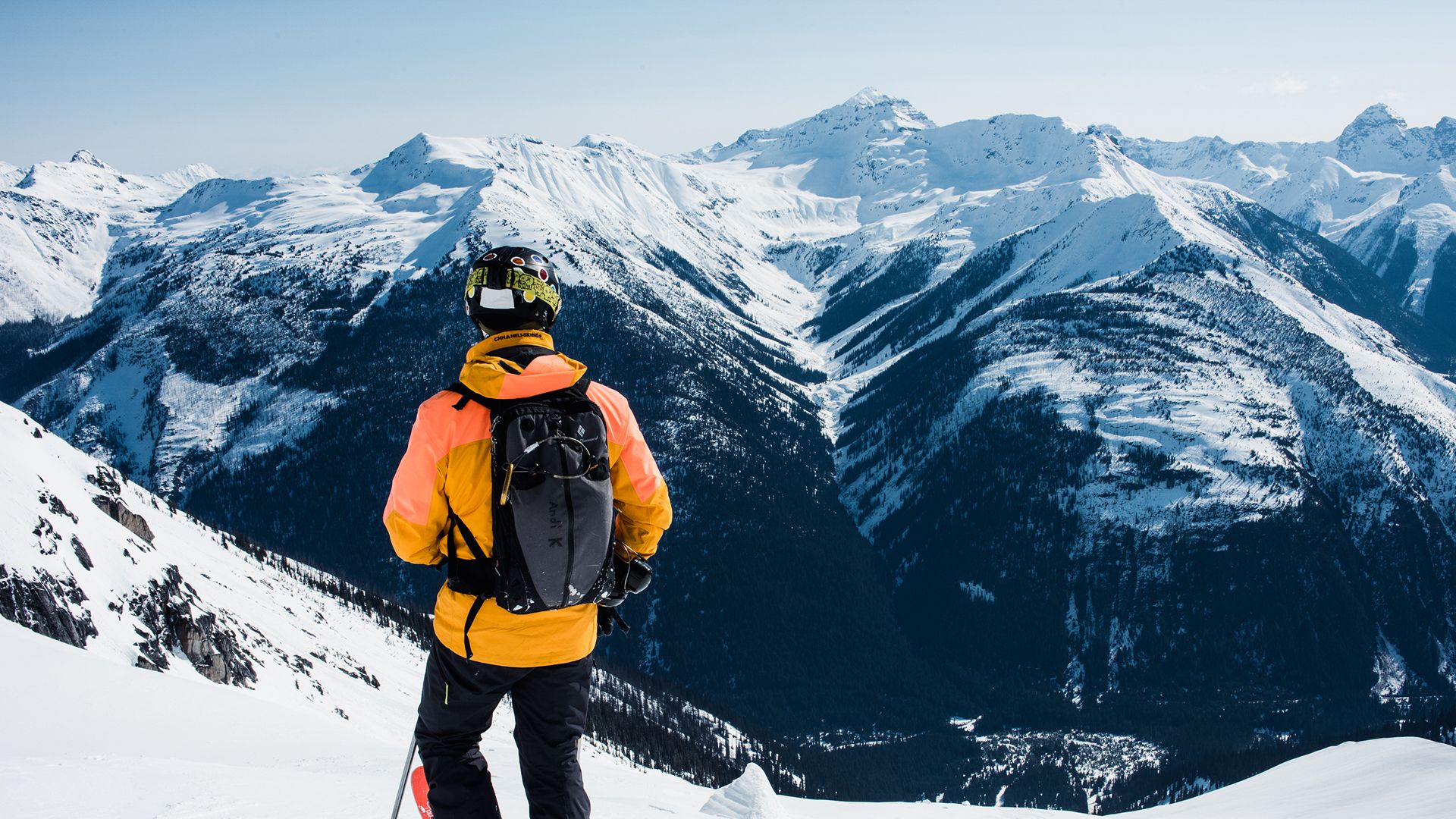 Ski guide taking in the view and looking out at a scene of snowy mountains in the distance.