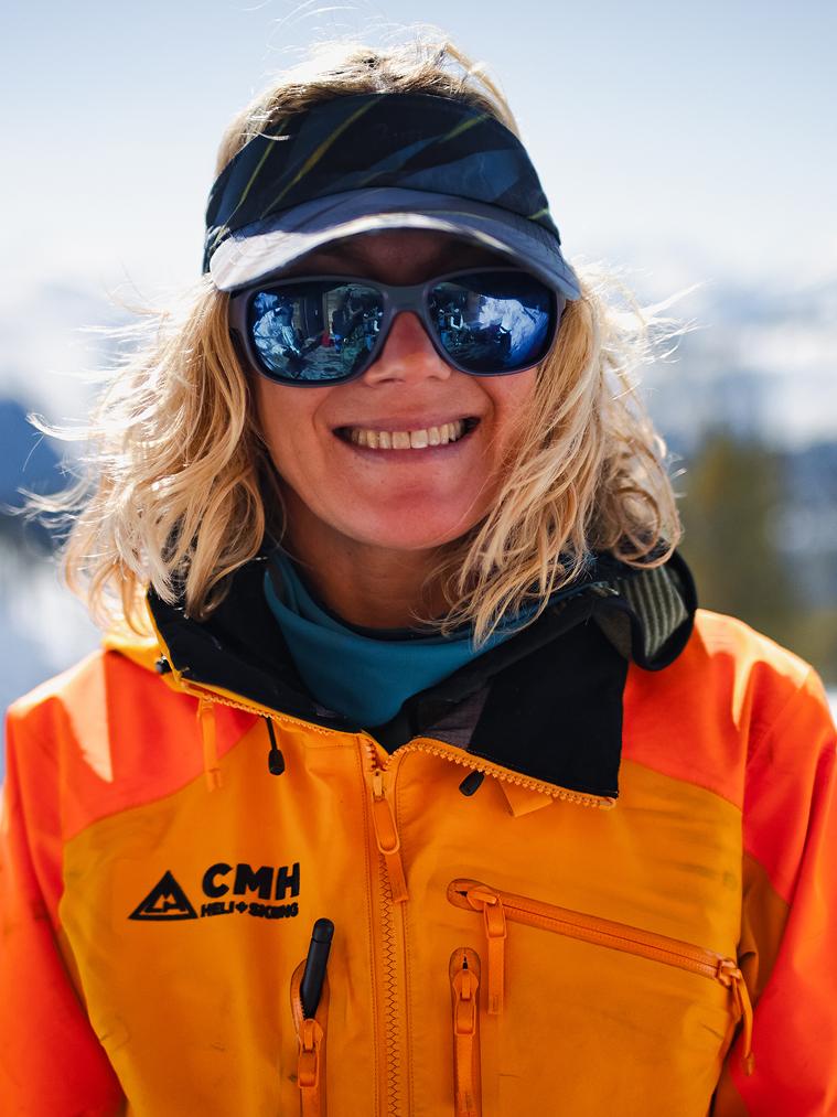 A CMH ski guide smiling and wearing an orange jacket