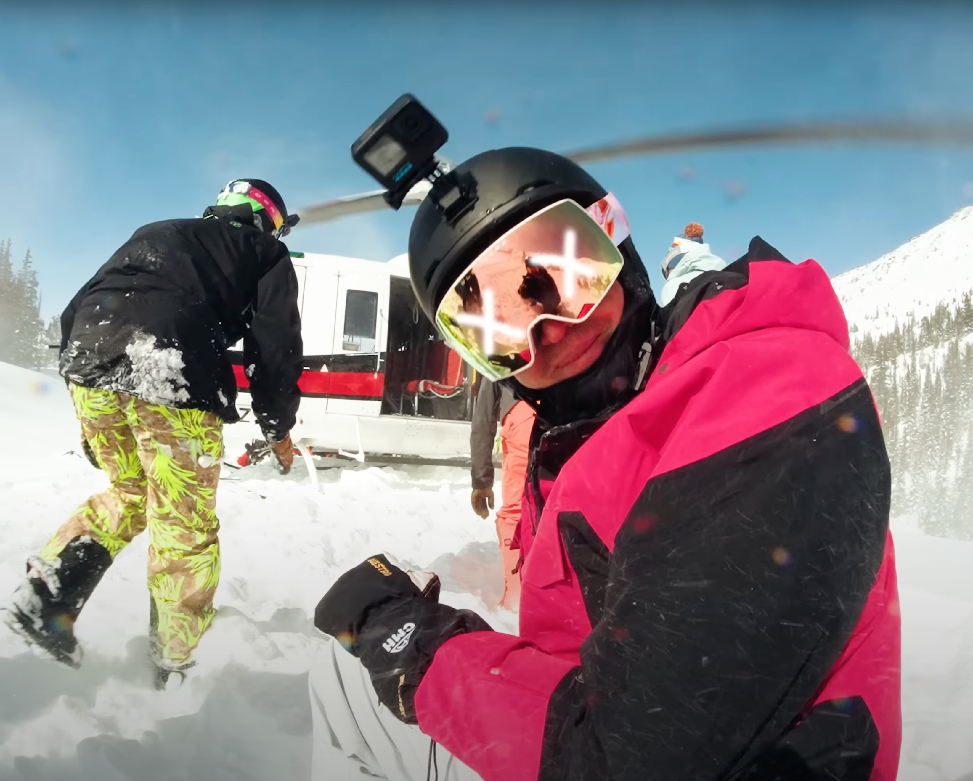 A skier kneeling by a helicopter