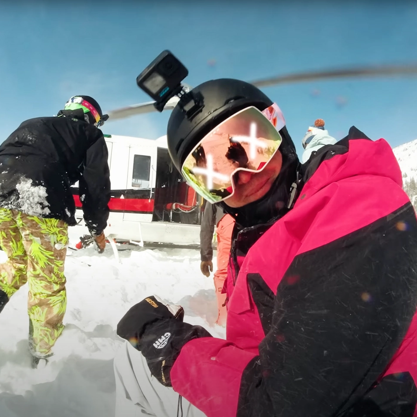 A skier kneeling by a helicopter