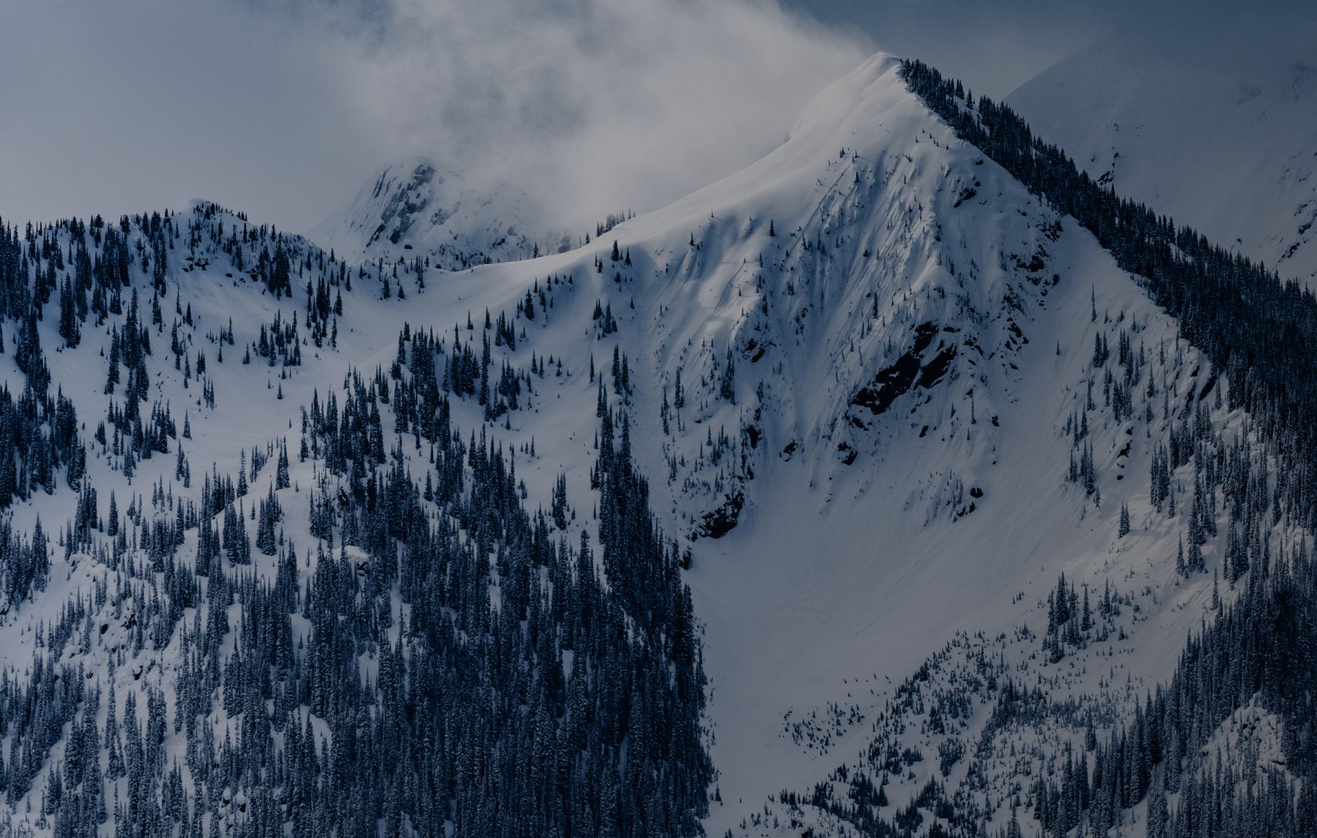 mountain range covered in snow and under a cloud 