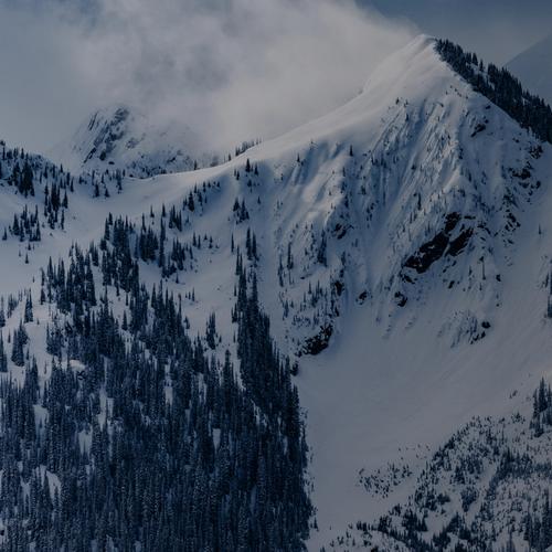 mountain range covered in snow and under a cloud
