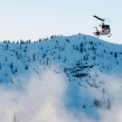 Helicopter flying over snowy mountains.