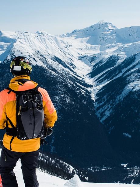 Ski guide taking in the view and looking out at a scene of snowy mountains in the distance.