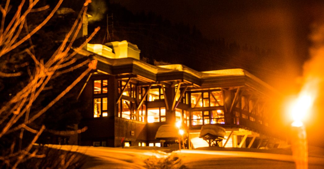 the warm illuminated exterior of a lodge at night offering a cozy retreat after a day of cmh heli-skiing adventure