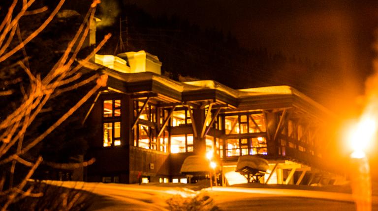 the warm illuminated exterior of a lodge at night offering a cozy retreat after a day of cmh heli-skiing adventure
