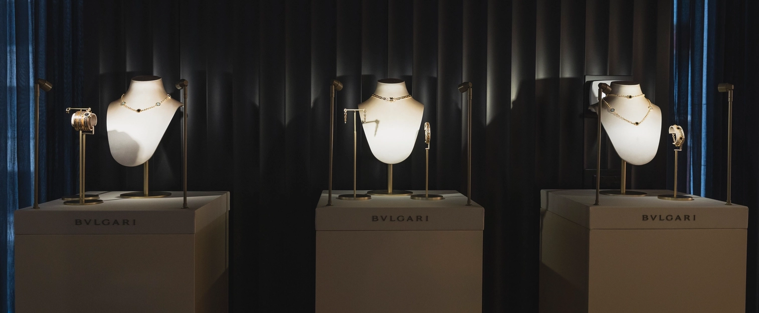 Bulgari high jewelry display featuring elegant gold necklaces, bracelets, and earrings showcased on illuminated busts in a luxurious boutique setting.