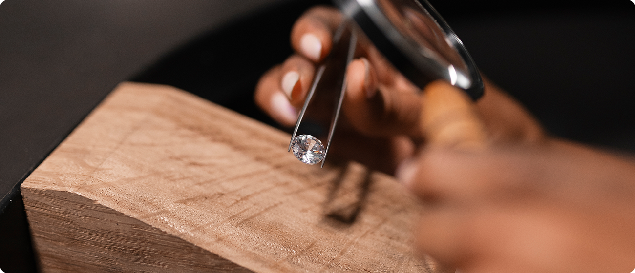 Un gemmologue inspectant de près un diamant brillant taillé avec une loupe et des pinces, assurant une qualité supérieure.